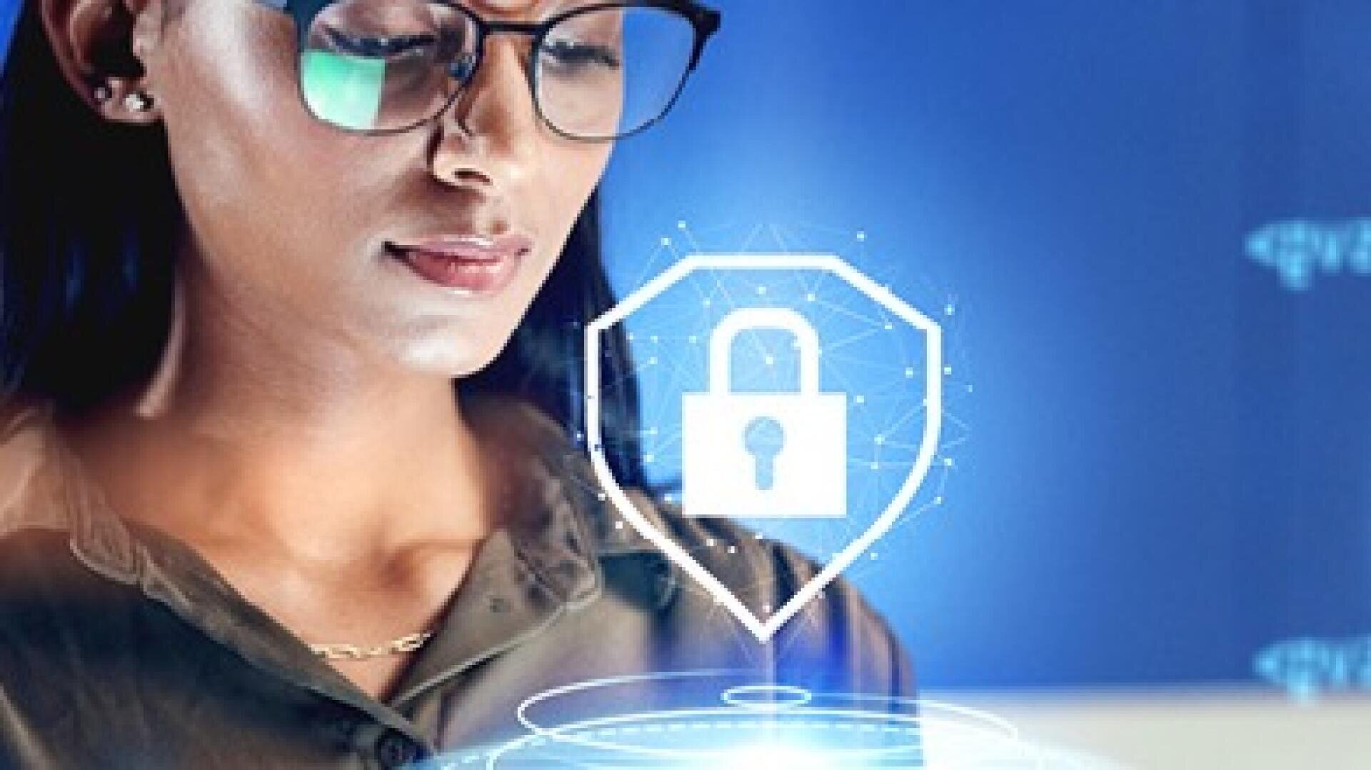 A woman wearing glasses looks at a computer screen, with a digital padlock icon in a shield overlayed, symbolizing cybersecurity or data protection.