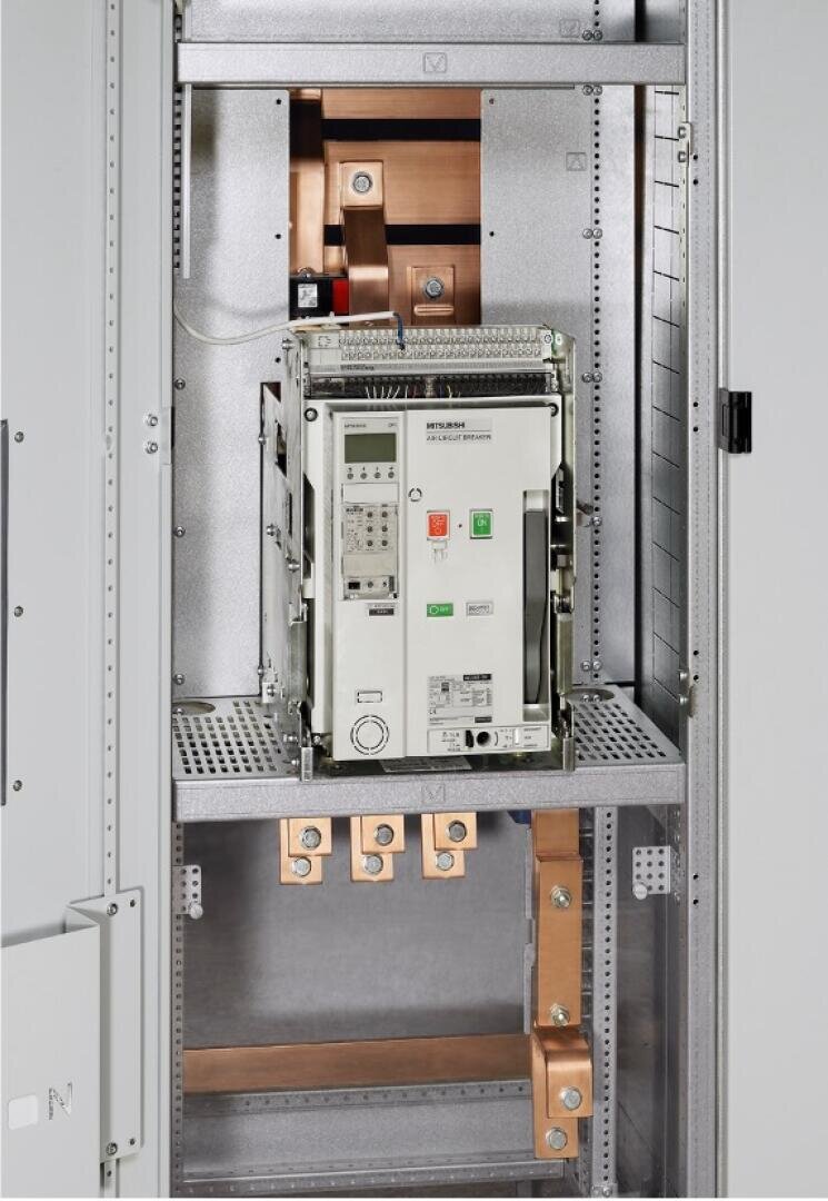 Nahaufnahme einer elektrischen Schalttafel mit einem großen Leistungsschalter. Zu sehen sind Bedienknöpfe, Anzeigeleuchten und dicke Kupferschienen für elektrische Hochspannungsverbindungen in einem Metallgehäuse.