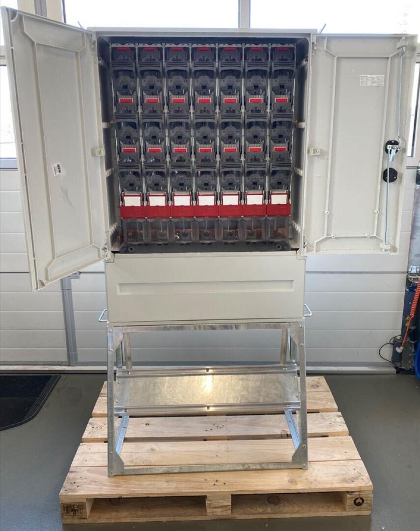 Eine offene Schalttafel mit vielen Sicherungshaltern, montiert auf einem Metallständer, auf einer Holzpalette.