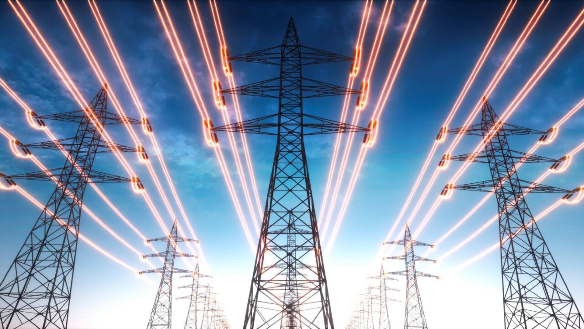 Tall electrical transmission towers with glowing power lines stretch into the distance against a blue sky, symbolizing energy distribution and high-voltage electricity.