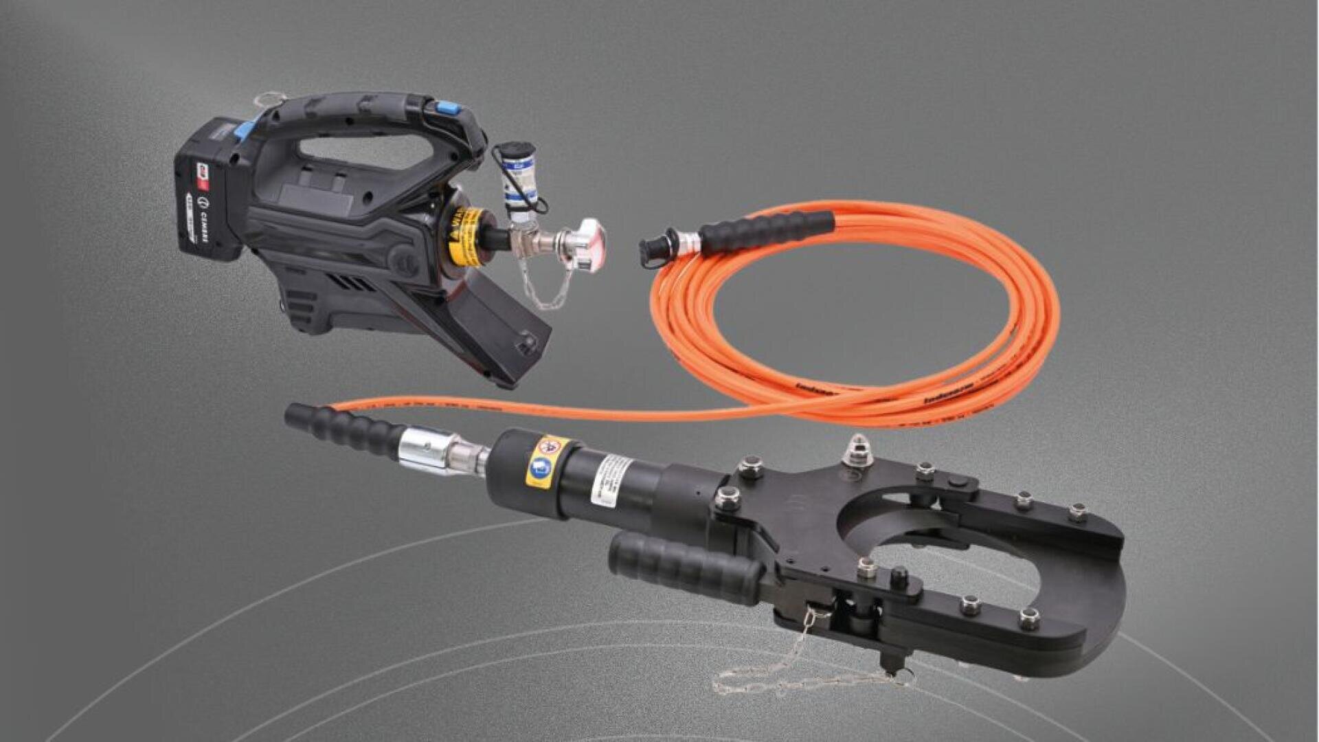 Ein tragbares hydraulisches Schneidgerät mit einem schwarzen Motor, der durch einen langen orangefarbenen Schlauch mit einem schwarzen Hochleistungsschneidkopf mit Griffen verbunden ist, dargestellt auf grauem Hintergrund.