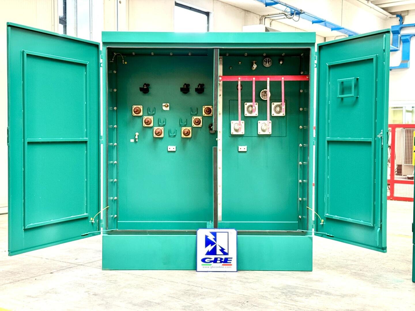 Ein offener, tealgrüner Schaltschrank mit zwei Fächern und sichtbaren Schaltern, Sicherungen und Diagnosemessgeräten. Auf dem Sockel befindet sich ein GBE-Logo.