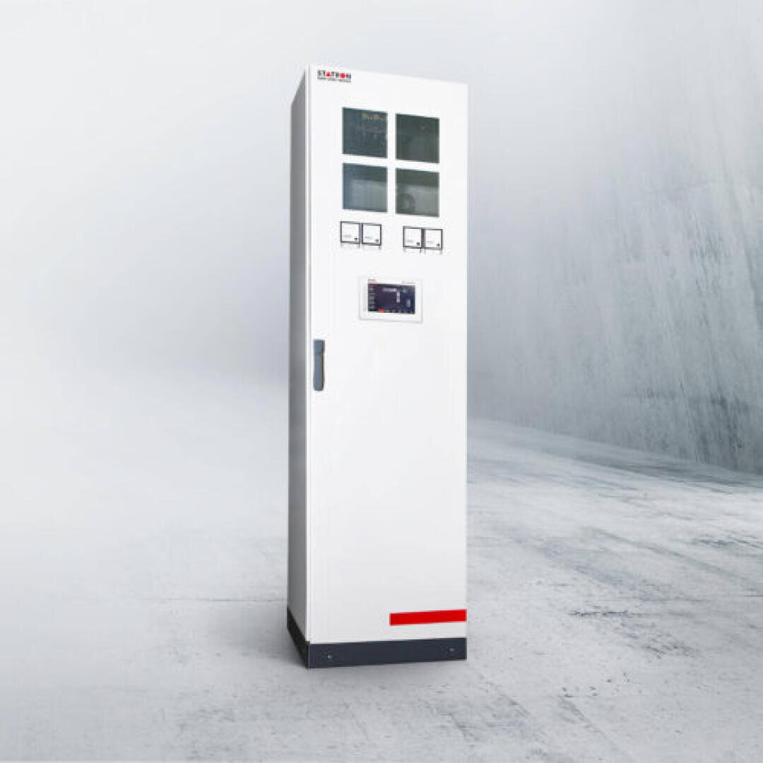 Ein hoher, weißer Schaltschrank mit Zählern und Bildschirmen an der Vorderseite, der auf einem sauberen, leeren Betonboden in einem minimalistischen, grau getönten Raum steht.