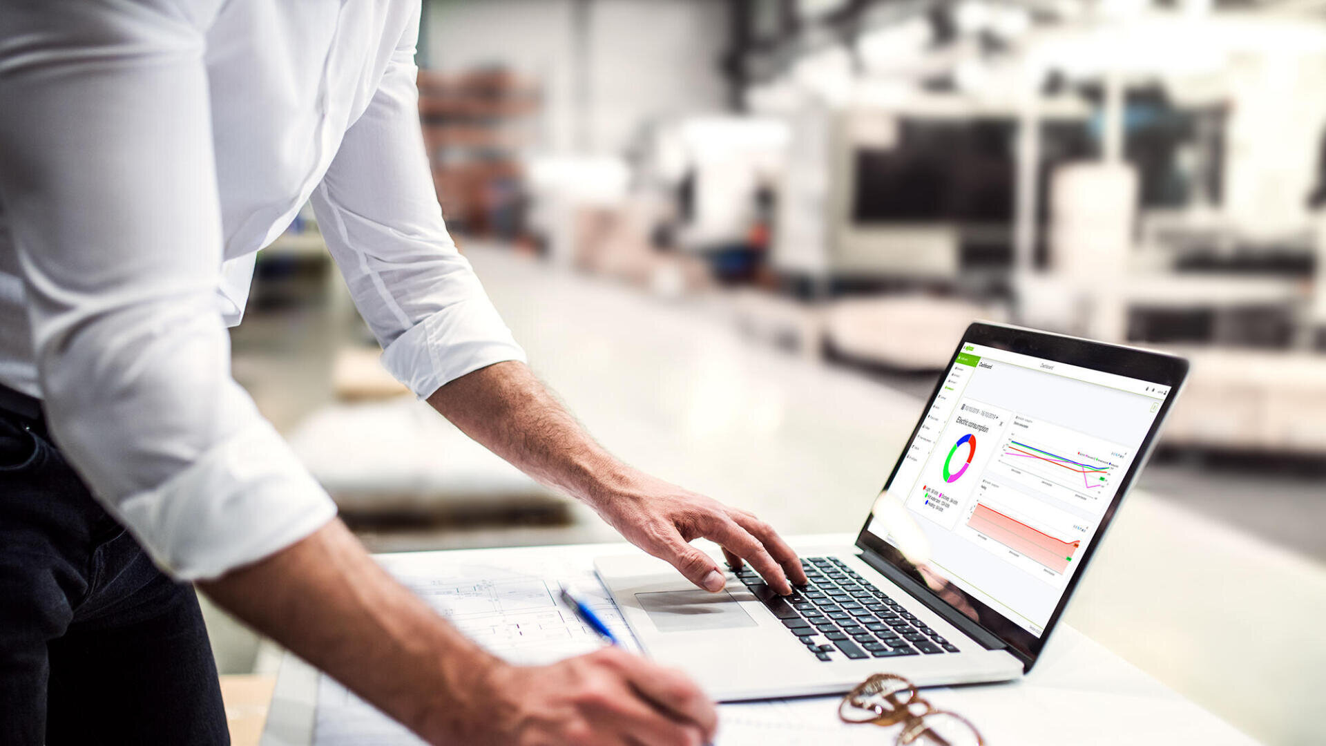 Eine Person arbeitet an einem Laptop mit Energie- und Verbrauchsanalysen auf dem Bildschirm. Die Illustration zeigt den Einsatz digitaler Werkzeuge für Energiedatenmanagement, Analyse und Monitoring in industriellen Anwendungen.