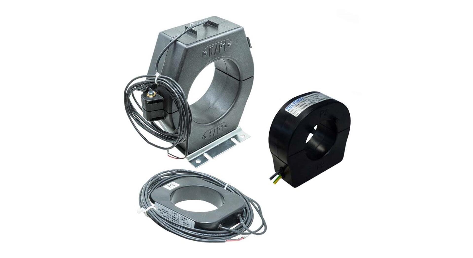 Auf weißem Hintergrund sind drei verschiedene Stromwandler abgebildet, jeder mit einer kreisförmigen Öffnung in der Mitte und angebrachten Drähten für elektrische Anschlüsse.