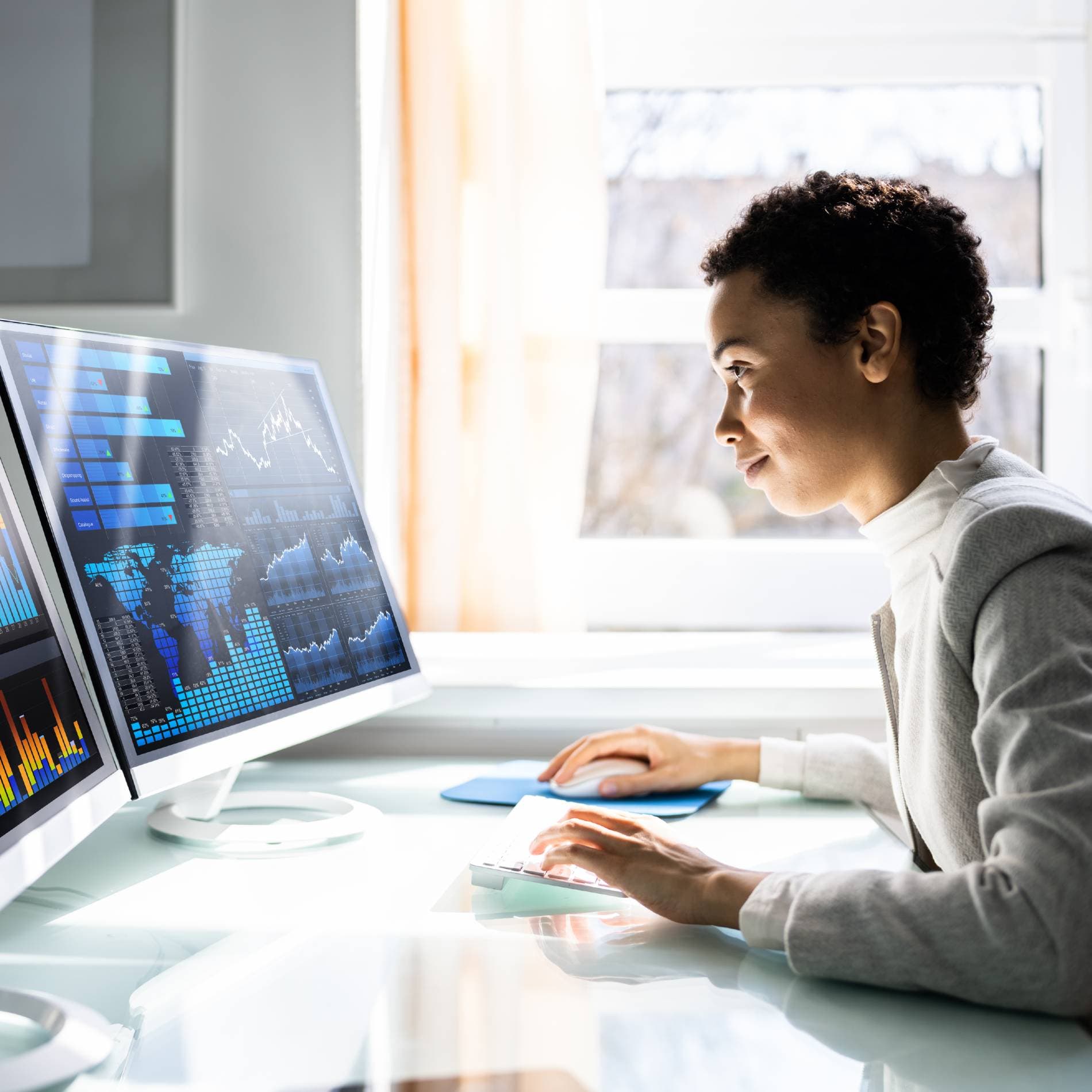 Eine Frau Blickt auf einen Computer-Monitor an ihrem Arbeitsplatz.