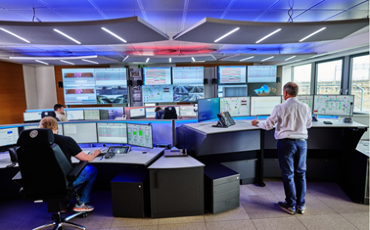 Ein moderner Kontrollraum mit Menschen, die mehrere große Bildschirme überwachen