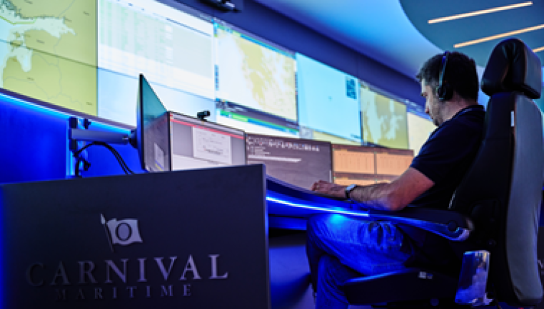 Eine Person mit Kopfhörern überwacht mehrere Computerbildschirme in einem Kontrollraum